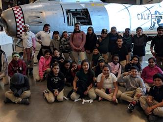Students pose in front of a plane