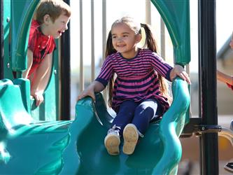 preschool girl sliding down slide