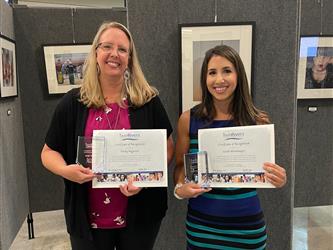 two female teachers holding awards
