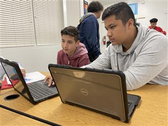Two students with laptops in the classroom