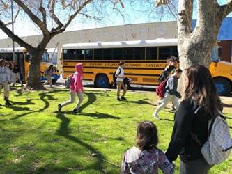 Students waling on grass at Smythe in front of EV school bus 