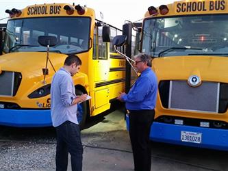 Tim Shannon speaking with reporter in front of Electric Bus 